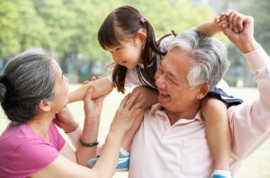 an elderly couple with a toddler on his shoulders